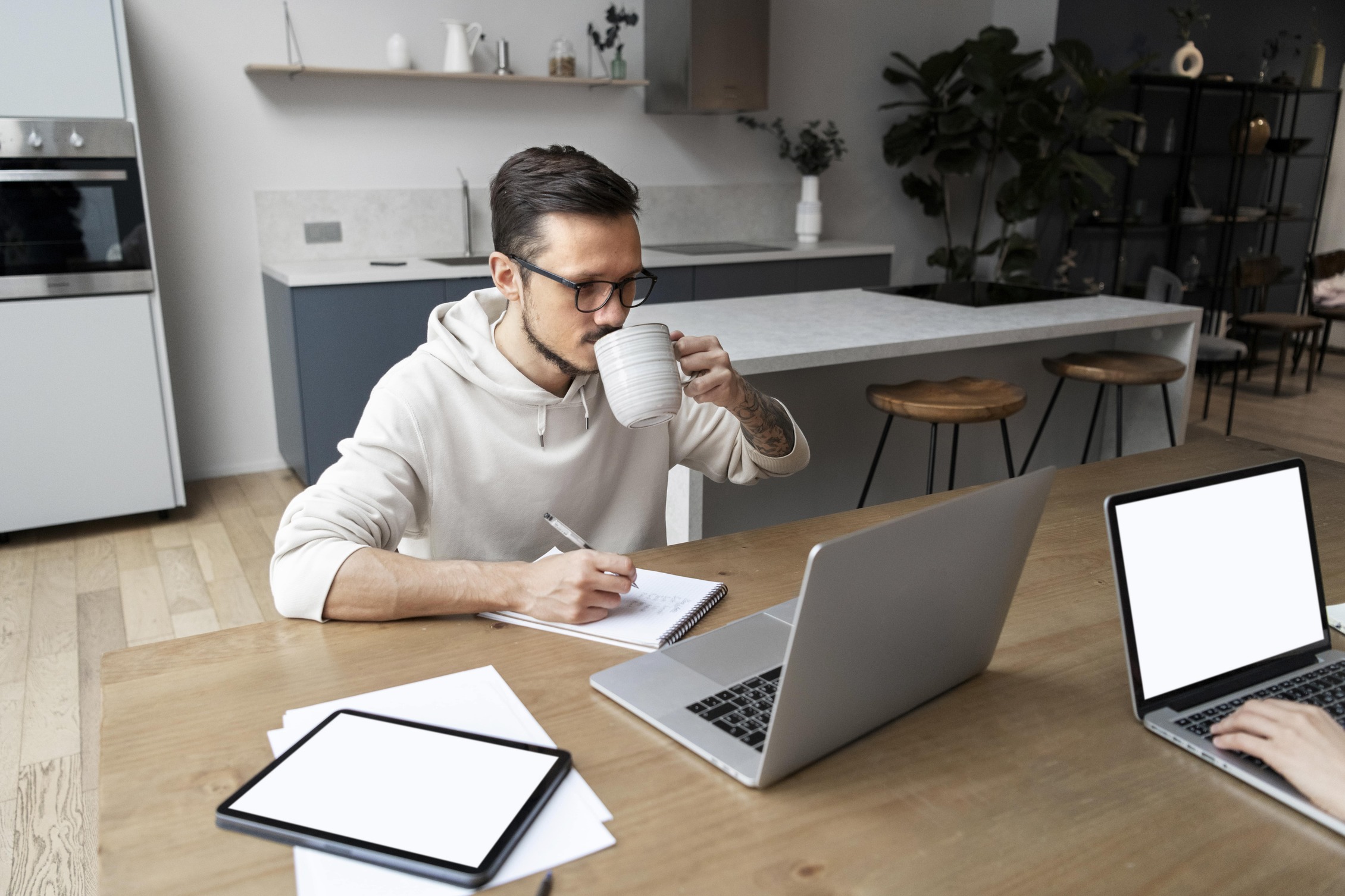 man-working-from-home-desk-while-having-drink